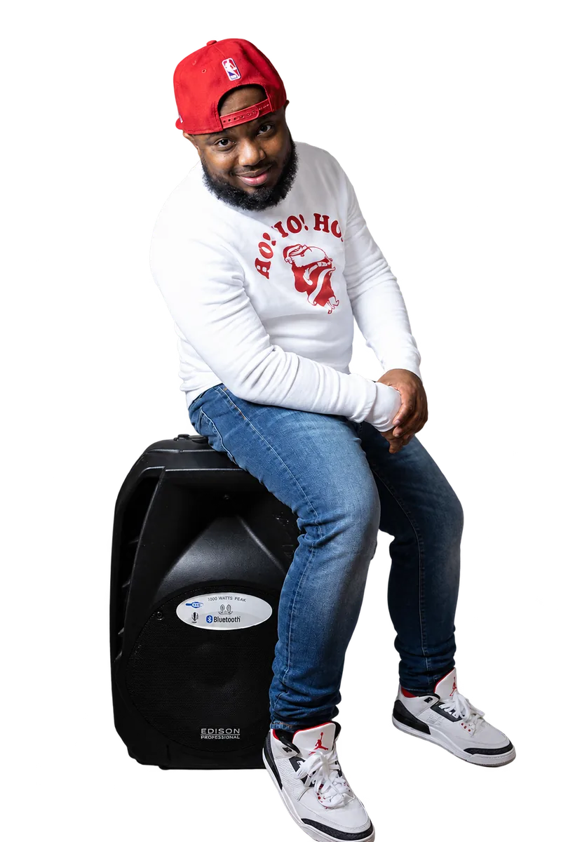 DJ Q Luv seated on a speaker