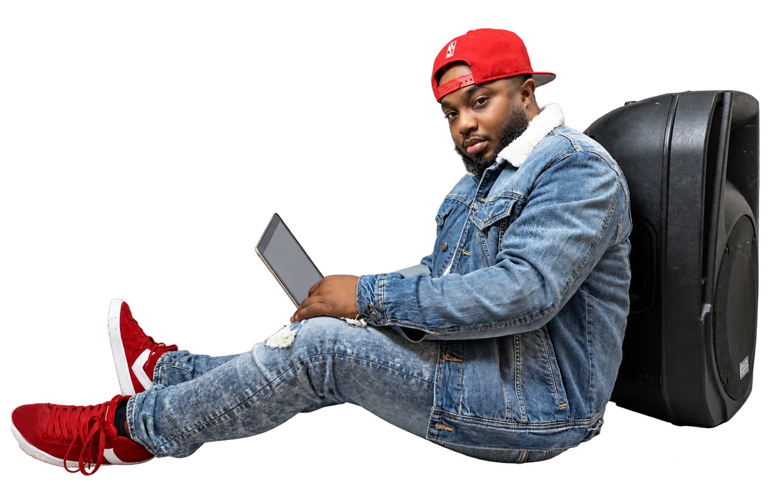 DJ Q Luv seated against a speaker holding an iPad